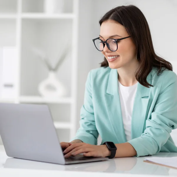 Wordpress: Eine Frau im türkisen Blazer sitzt vor einem Laptop